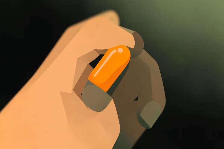 Close-up de uma pessoa segurando uma cápsula de vitamina entre o polegar e o indicador, com foco suave no fundo.